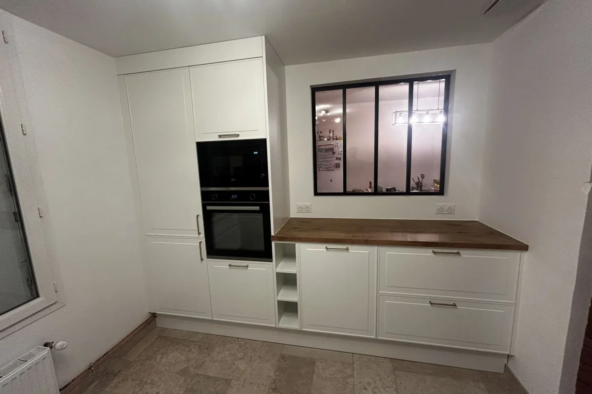 Colonne de cuisine blanche avec four et micro-ondes encastrés à côté d'une verrière intérieure.