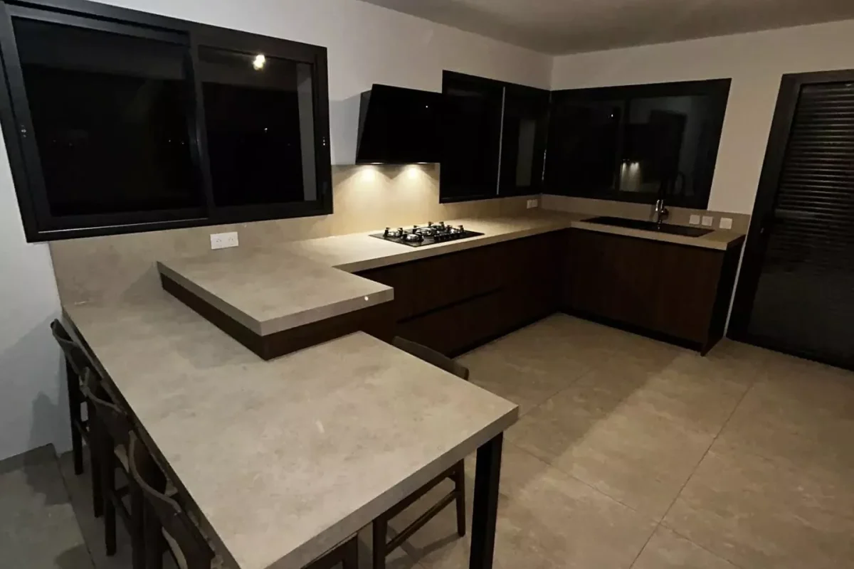 Grande cuisine moderne en bois de noyer avec îlot central et plan de travail effet béton gris.