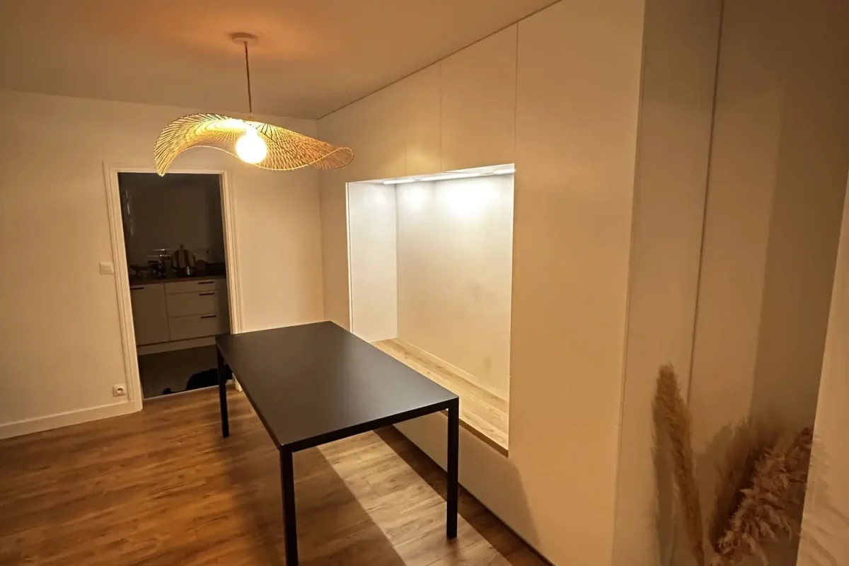 Salle à manger moderne avec table noire, meuble de rangement blanc intégré et suspension en rotin